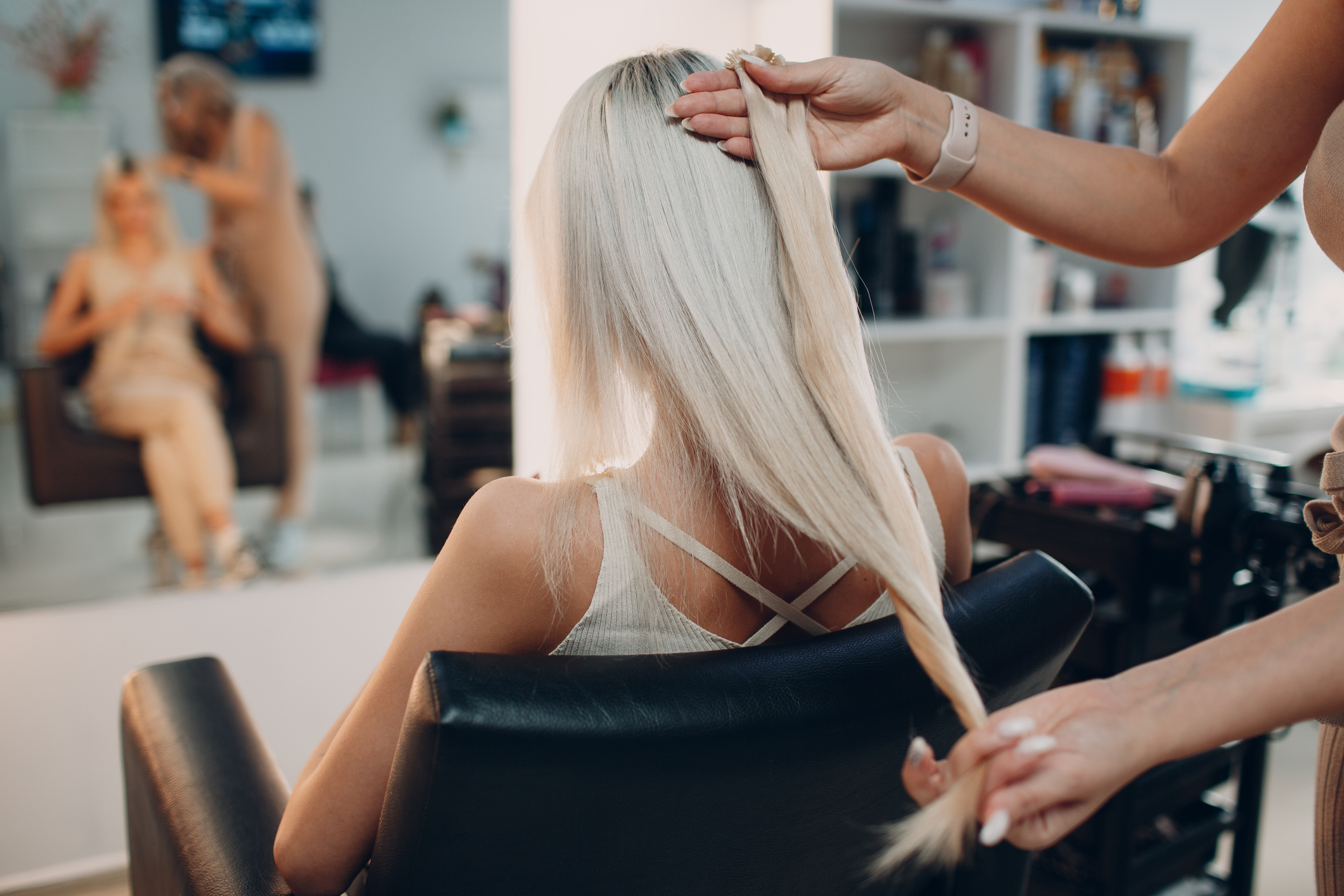 Hairdresser female making hair extensions to young woman with blonde hair in beauty salon. Professional hair extension. Hairdresser female making hair extensions to young woman with blonde hair in beauty salon. Professional hair extension.